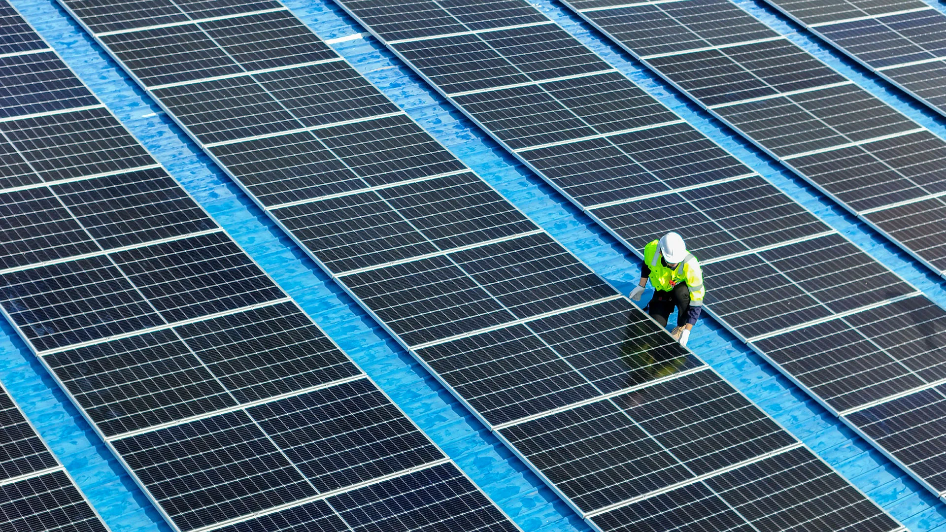 Solar Panels for Business - this image shows a commerical roof with solar panels installed and an engineer checking them