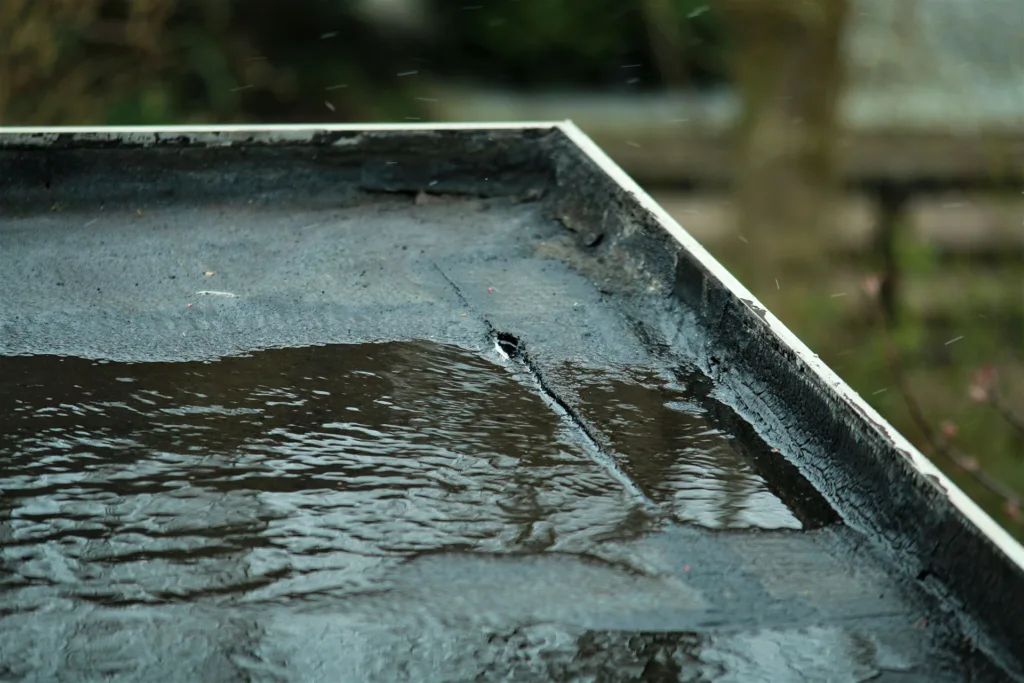 The 12 Hazards of Christmas - Essential Building Safety Tips for Commercial Premises this image shows a flat roof with water pooling and a tear in the fabric