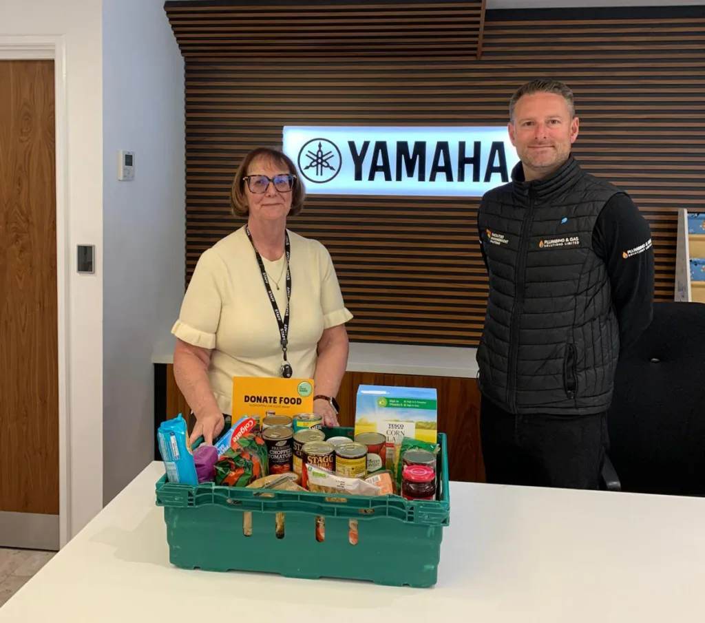 Yamaha team with MK Food Bank donation crate collected by FMS Team at reception desk in Milton Keynes