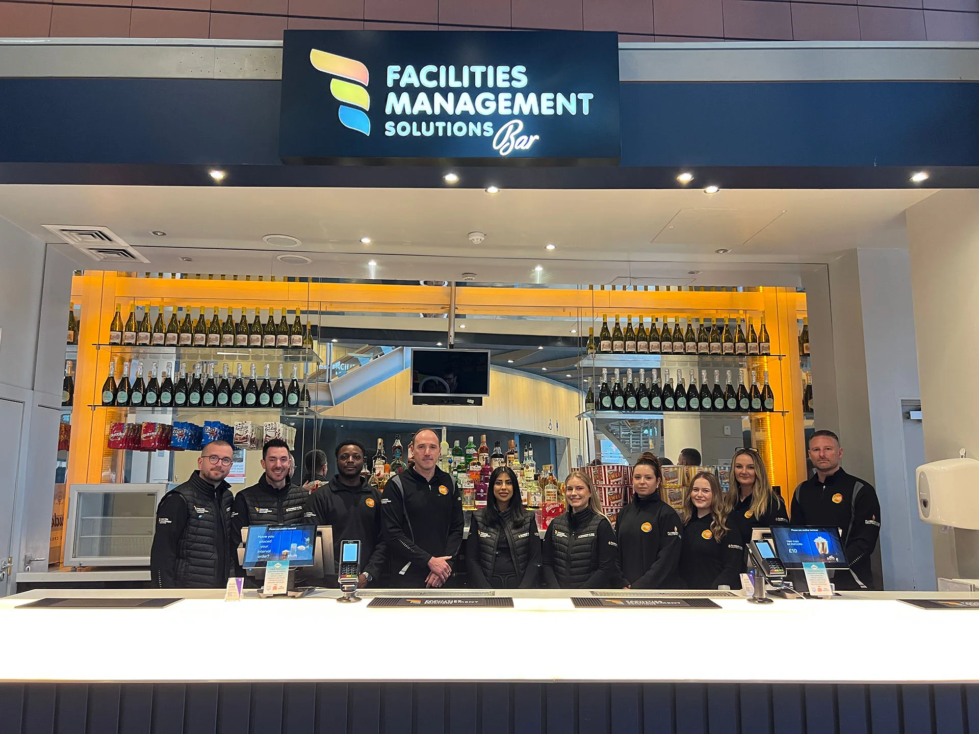FMS team standing behind the Facilities Management Solutions Bar at Milton Keynes Theatre during the VIP Selfie Competition campaign launch